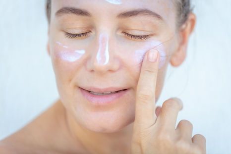 A woman applying sea moss gel to her face as a soothing mask